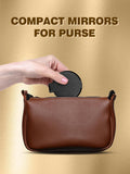 a hand holding a round compact mirror above a brown purse