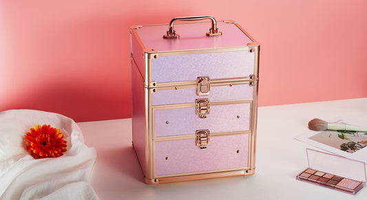 Pink and rose gold makeup box with detachable LED mirror and drawers on a pink background with makeup items around